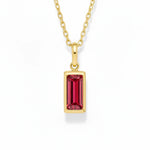gold july birthstone necklace with red cubic zirconia on a white background.