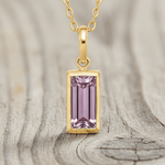 Gold necklace with a pink gemstone pendant on a white background