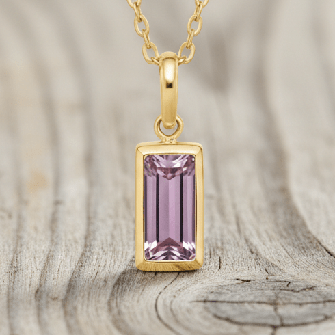 Gold necklace with a pink gemstone pendant on a white background