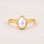 gold june birthstone ring featuring pear-shaped bezel-set natural mother of pearl 