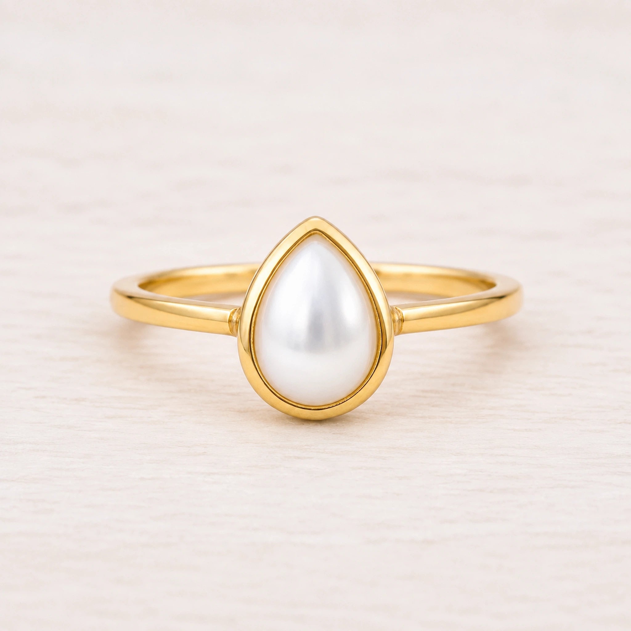 gold june birthstone ring featuring pear-shaped bezel-set natural mother of pearl 