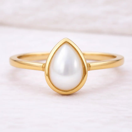 Gold ring with a teardrop-shaped pearl on a light background