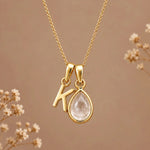 Gold initial K necklace with an April clear quartz teardrop on brown with dried flowers