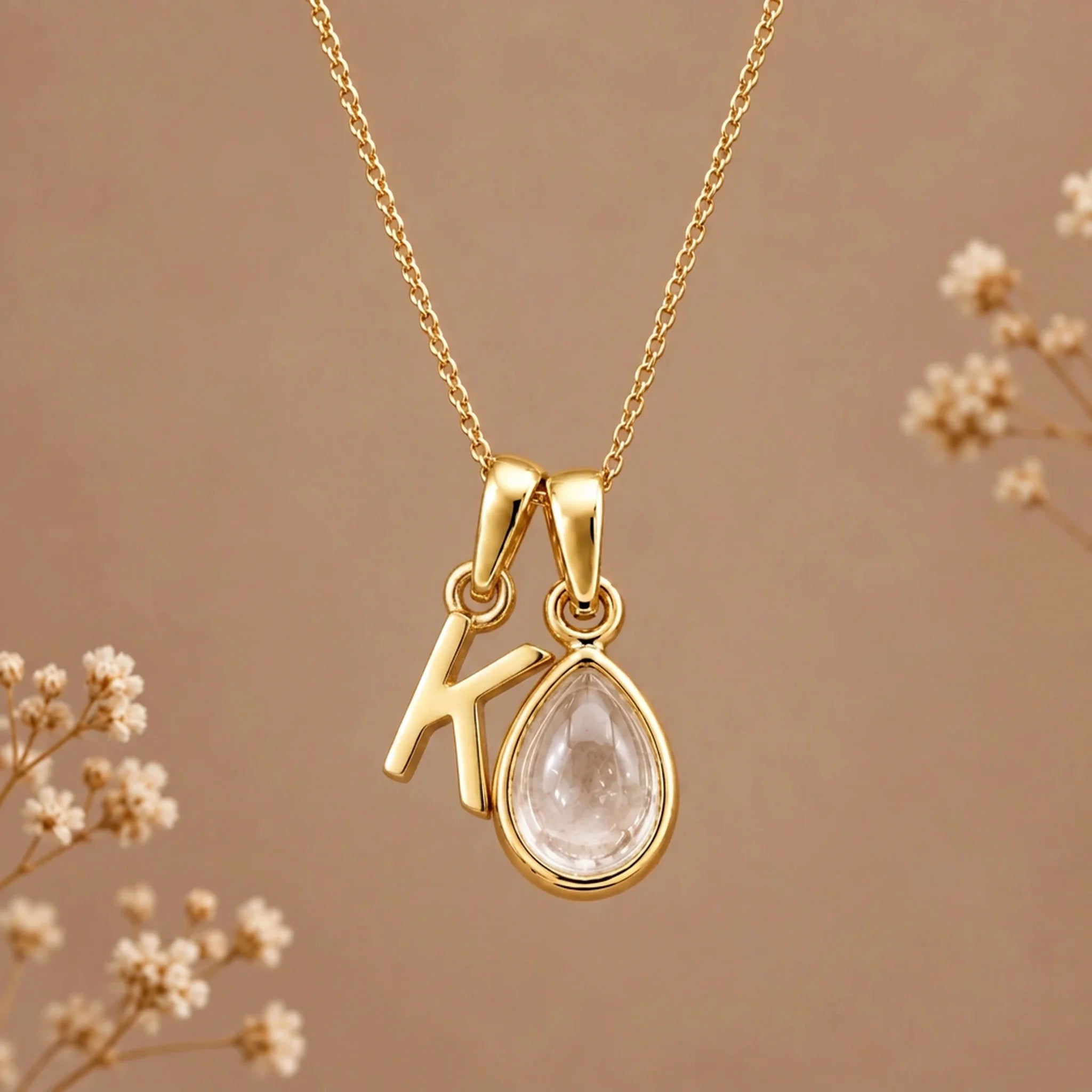 Gold initial K necklace with an April clear quartz teardrop on brown with dried flowers