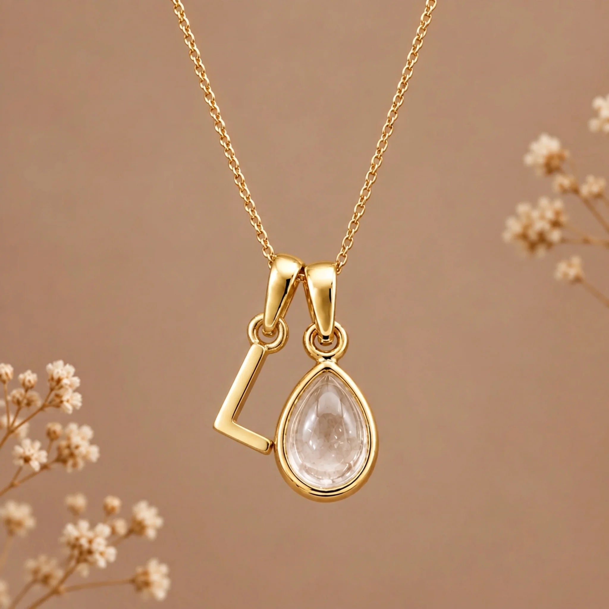 Gold initial L necklace with an April clear quartz teardrop on brown with dried flowers
