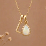 Gold Initial L Pendant and October birthstone Natural Opal Necklace against a warm background