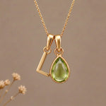 Gold Initial L Pendant and August birthstone Natural Peridot Necklace against a warm background
