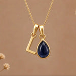 Gold Initial L Pendant and September birthstone Natural Sapphire Necklace against a warm background