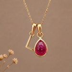 Gold Initial L Pendant and July birthstone Natural Ruby Necklace against a warm background