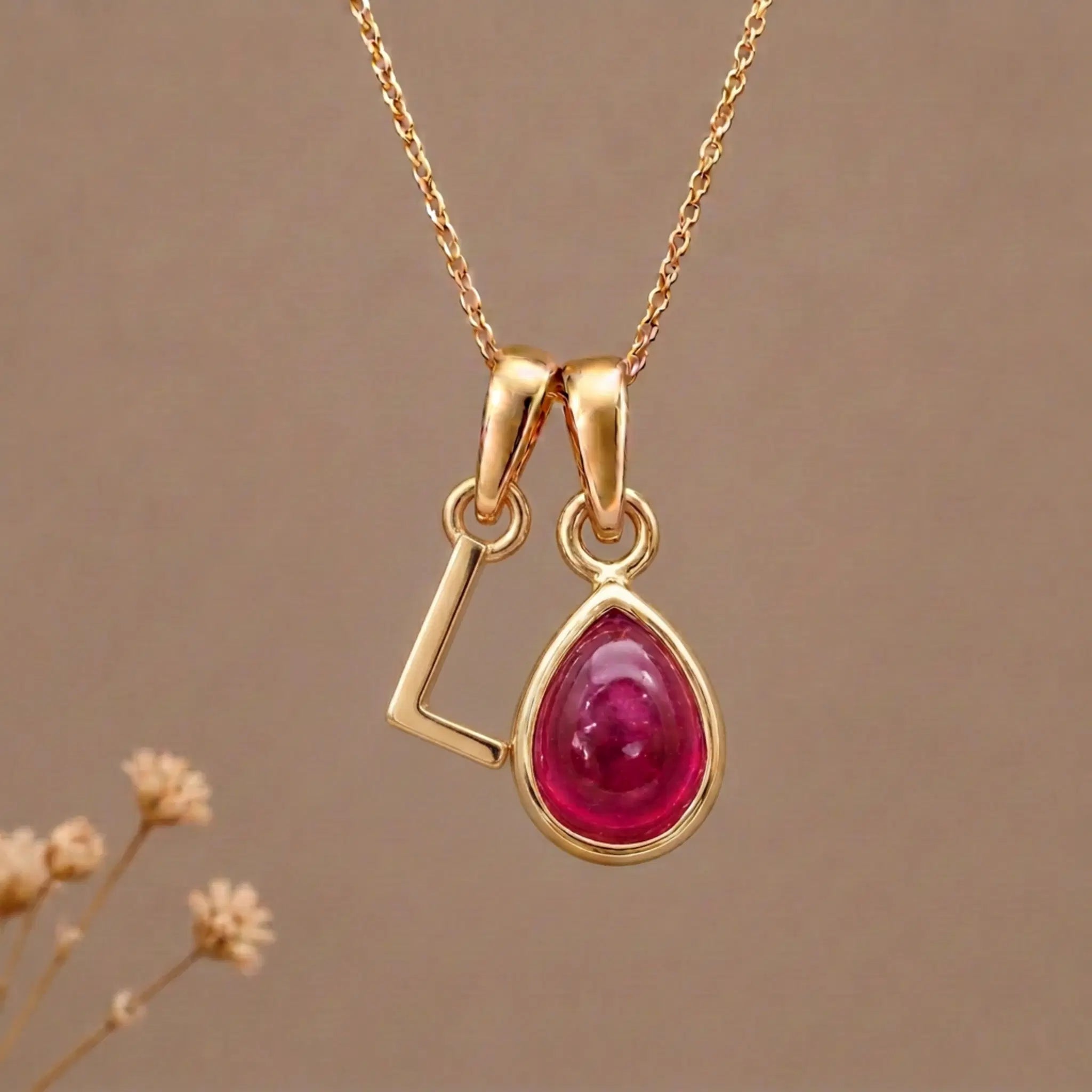 Gold Initial L Pendant and July birthstone Natural Ruby Necklace against a warm background