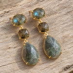 Pair of gold labradorite drop earrings on weathered wood, with oval, cushion and pear-shaped natural stones.