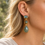 Gold labradorite drop earring worn in natural daylight, showing grey-green stones and a blue flash in the oval stud.