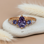 Gold ring with purple gemstone on a textured surface