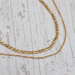Two gold chains on a light wooden surface
