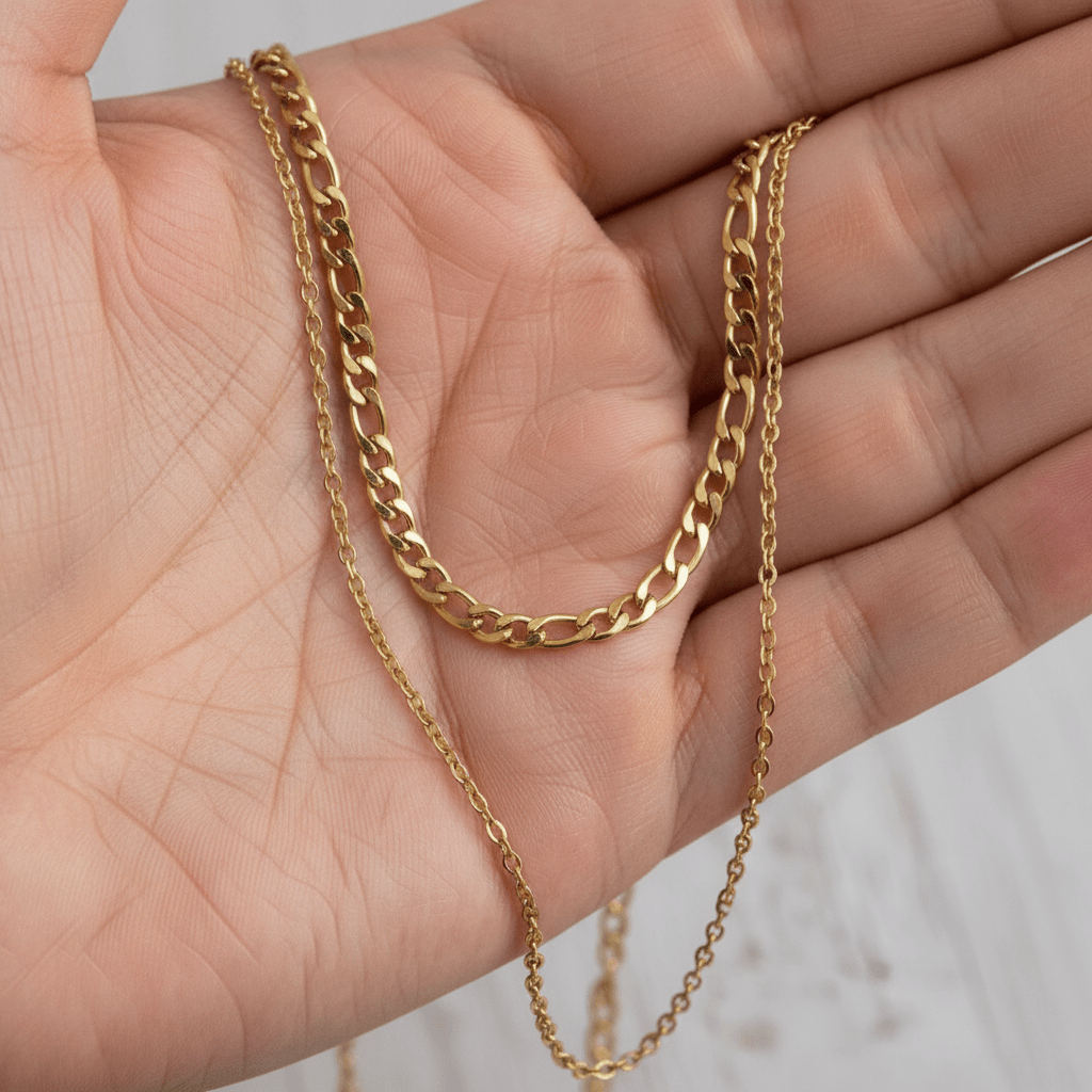Gold chain necklace held in a hand against a neutral background