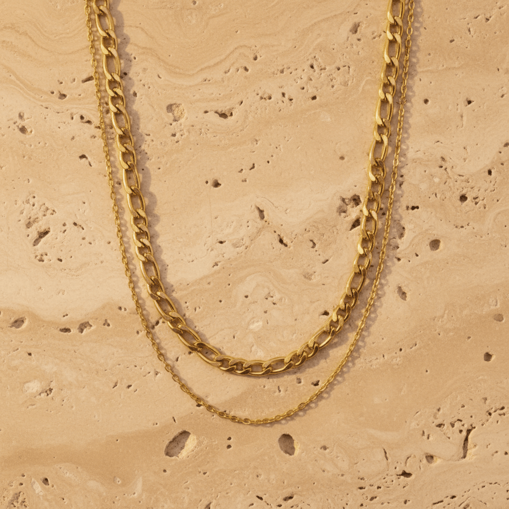 Gold chain necklace on a beige stone surface
