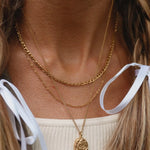 Close-up of a person wearing gold layered necklace 