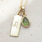 gold Necklace with a leo zodiac pendant and a august birthstone peridot pendant on a light background