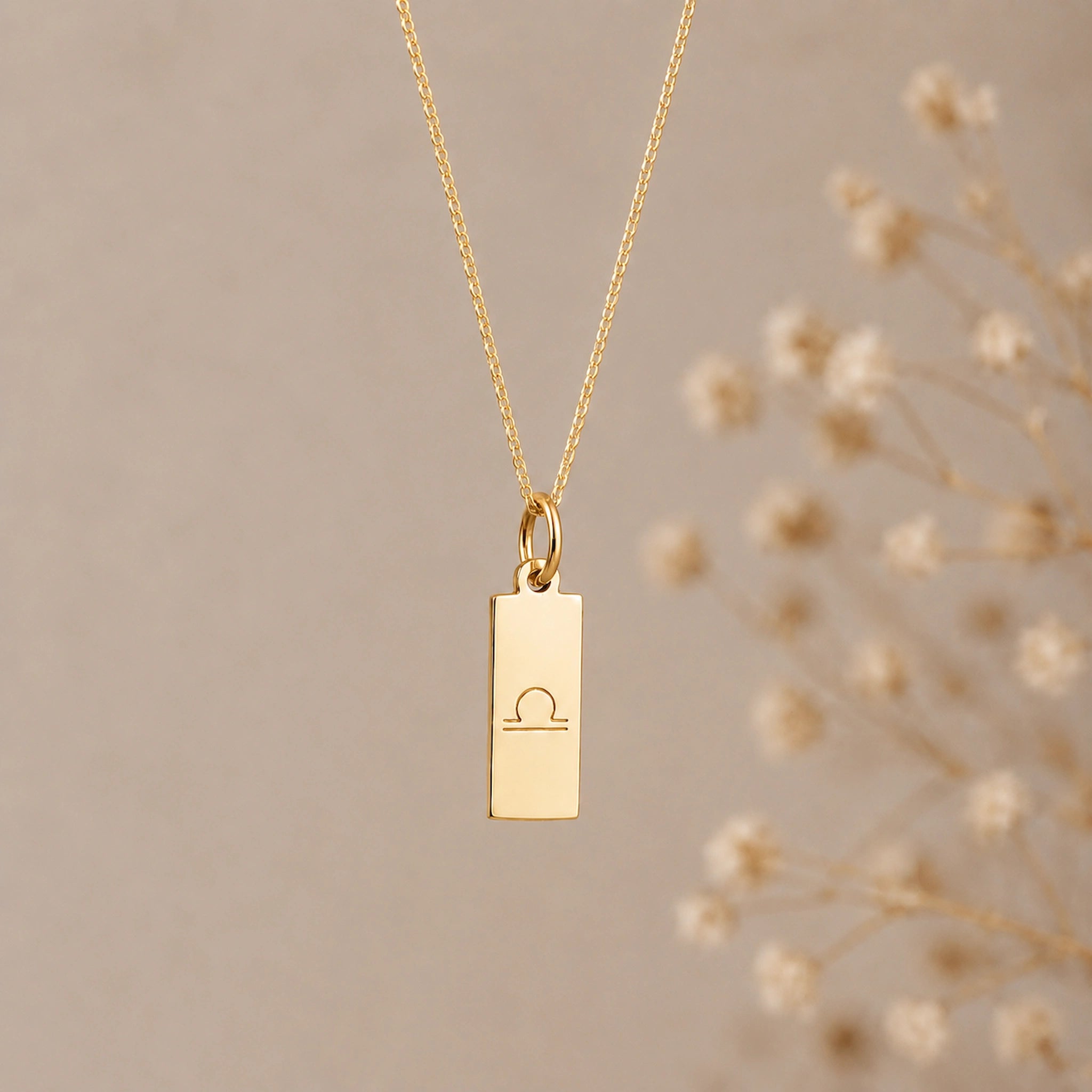 gold plated sterling silver Libra necklace with a minimalist libra zodiac sign line glyph engraved rectangular pendant on a fine chain against a light background