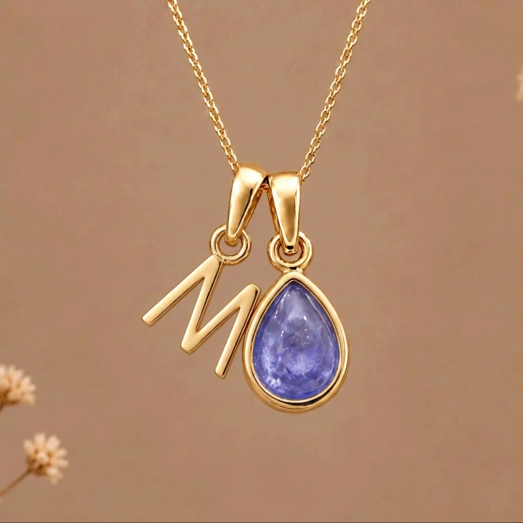 Gold Initial M and December Birthstone natural Tanzanite Necklace on a warm background