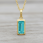 Gold necklace with a blue gemstone pendant on a white background