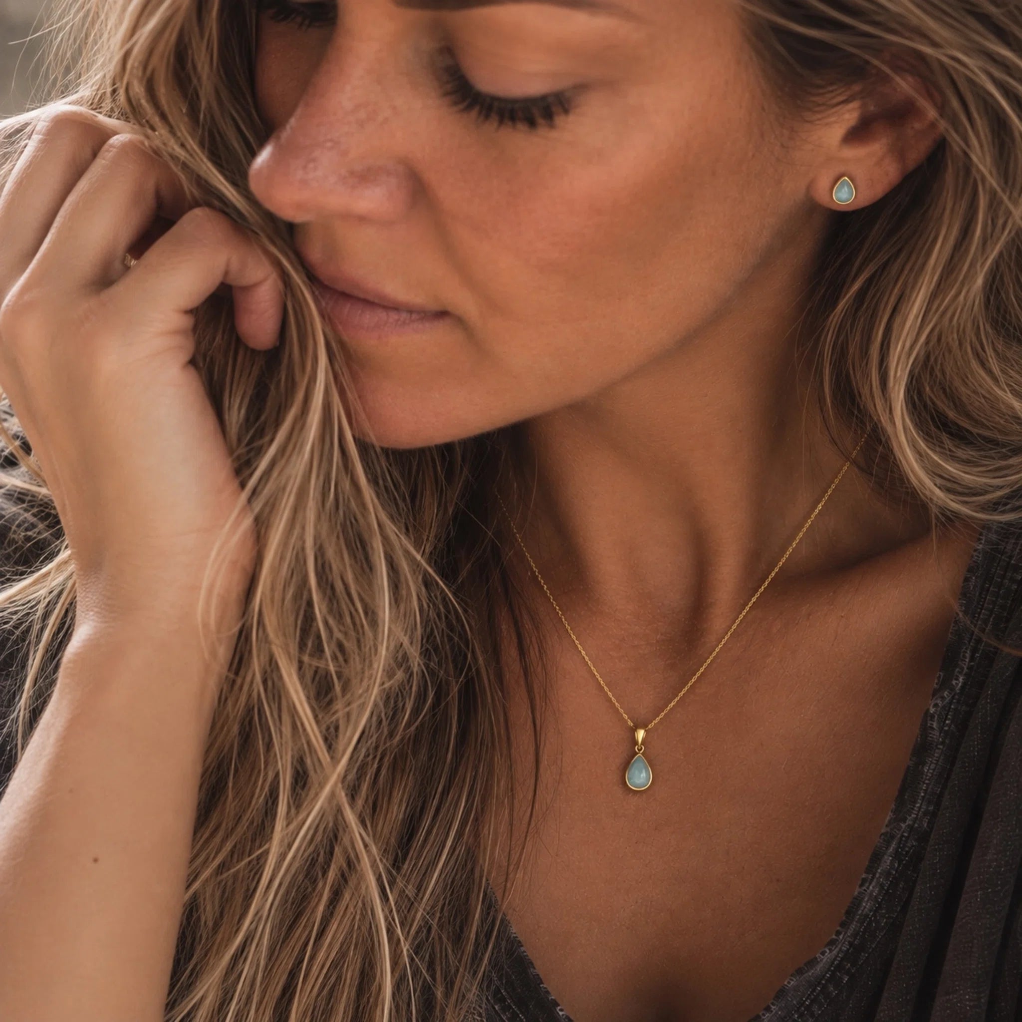model wearing gold march birthstone jewellery set of dainty natural aquamarine pendant necklace and matching stud aquamarine earrings