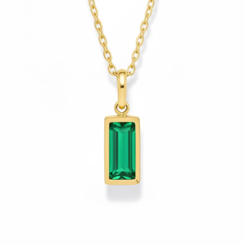 Gold necklace with a green gemstone pendant on a white background