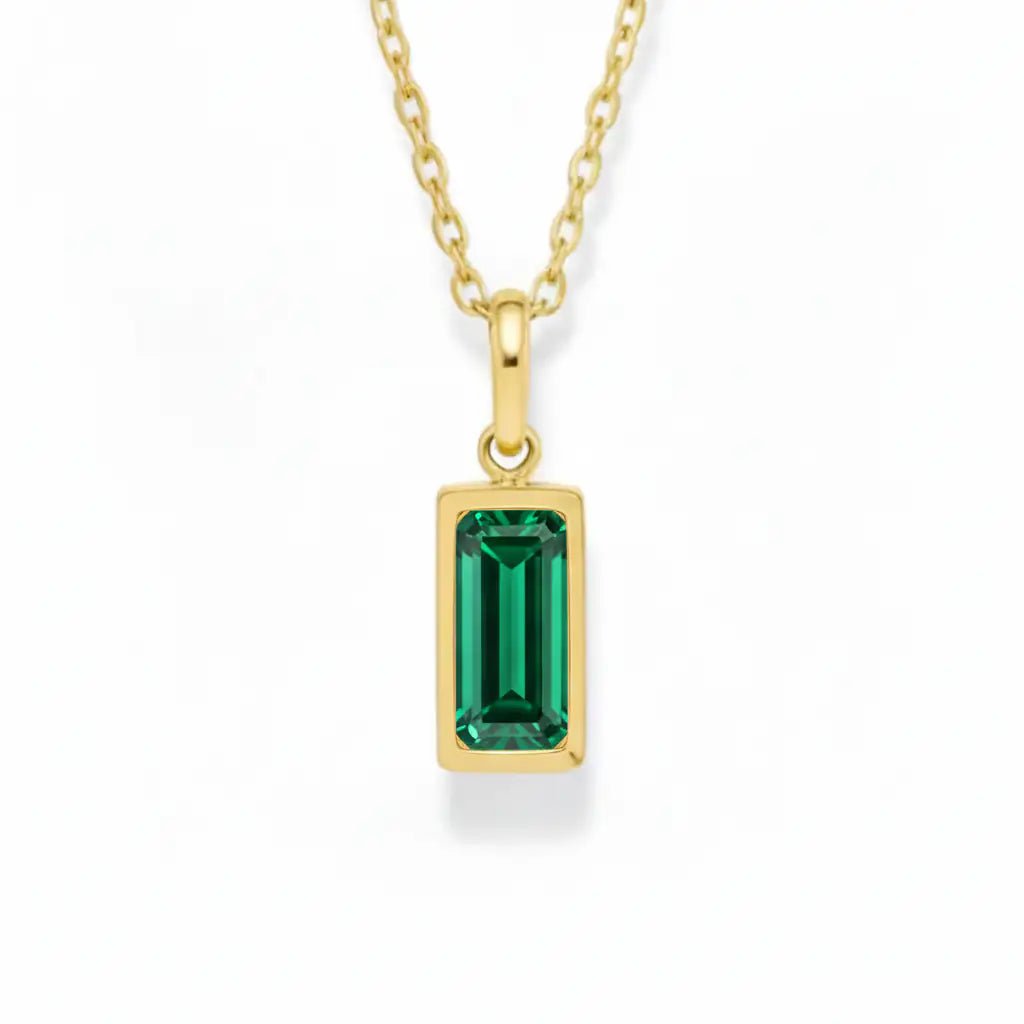 gold may birthstone necklace with green cubic zirconia on a white background.