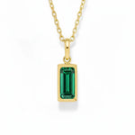 gold may birthstone necklace with green cubic zirconia on a white background.