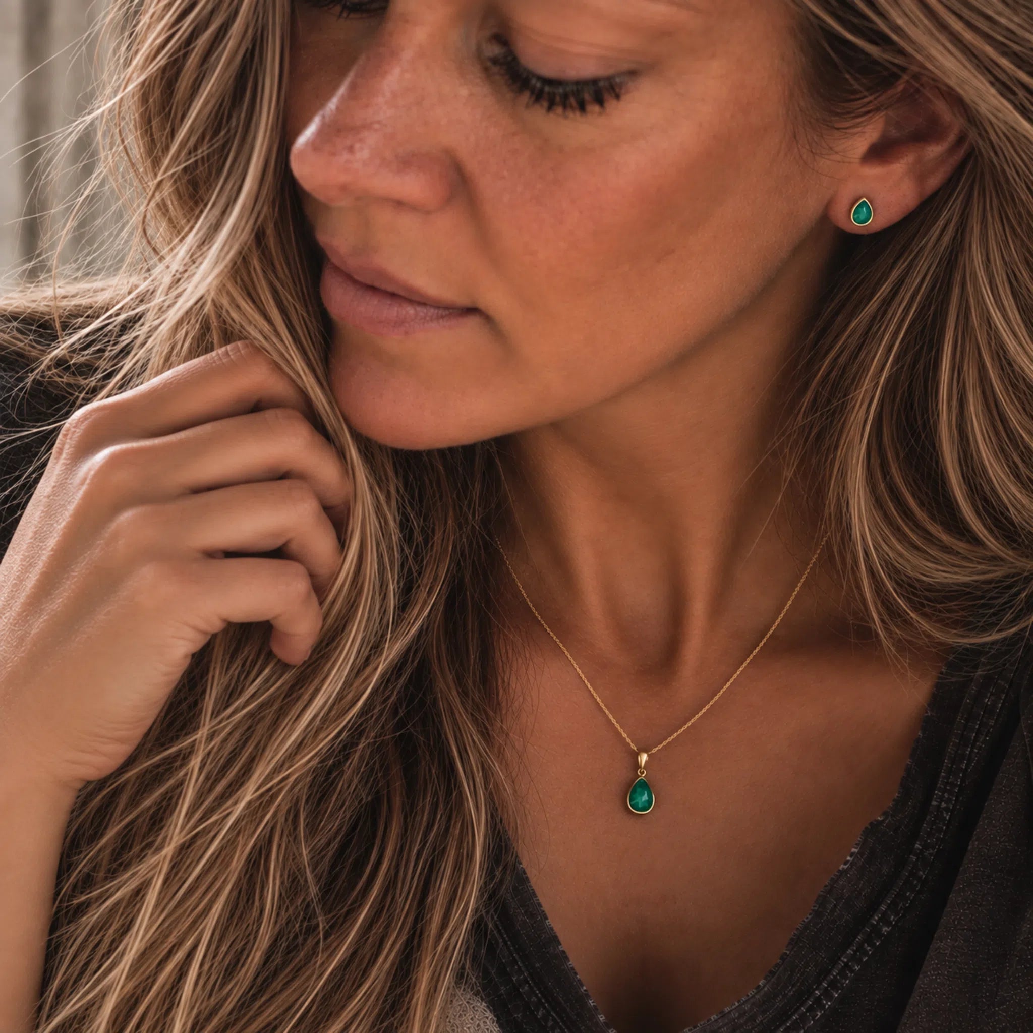 model wearing a gold may birthstone jewellery set of dainty natural emerald pendant necklace and matching stud emerald earrings