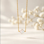 Gold mother of pearl clover necklace on a soft warm white background