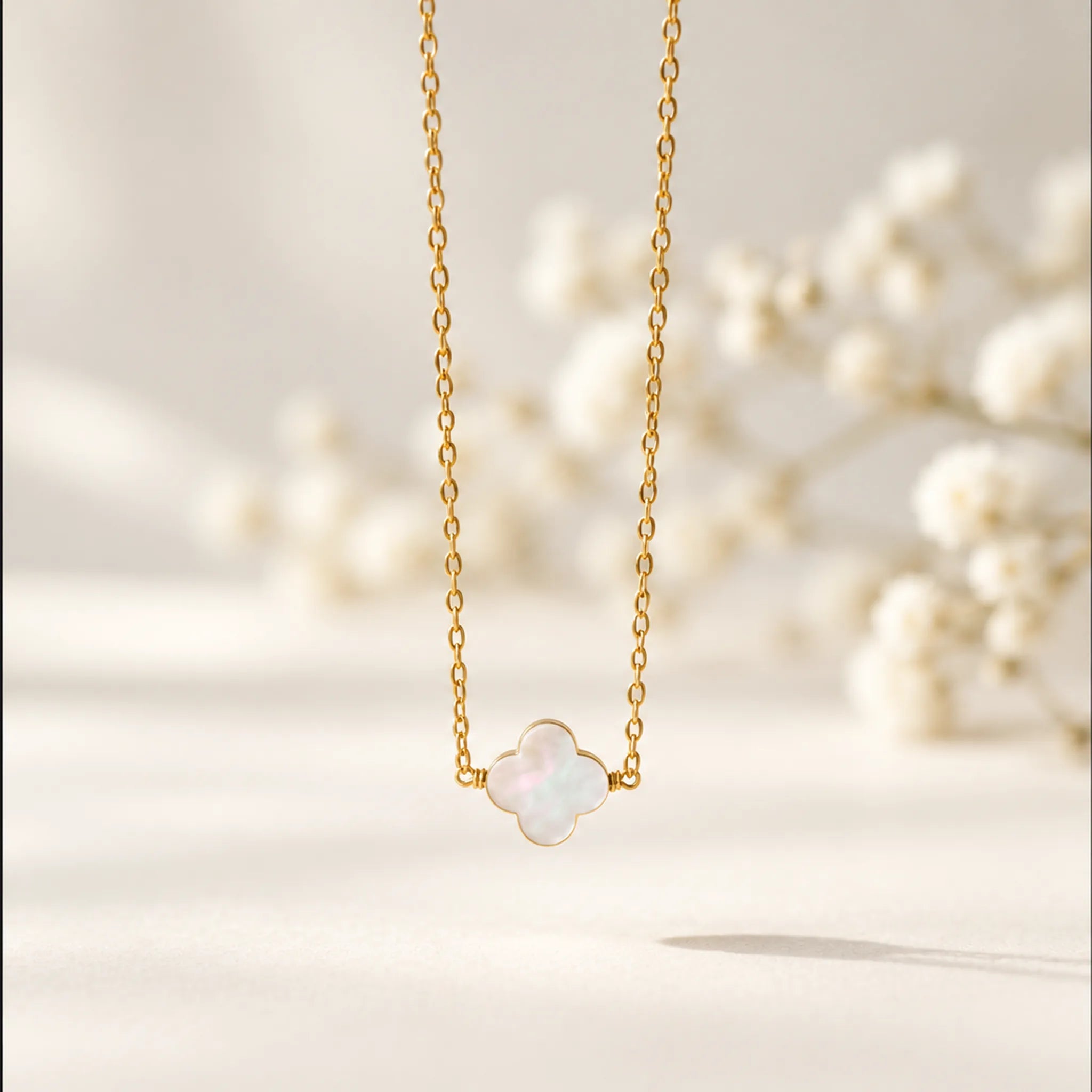 Gold mother of pearl clover necklace on a soft warm white background