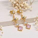 Gold multi gemstone drop earrings with pink rose quartz on a light background