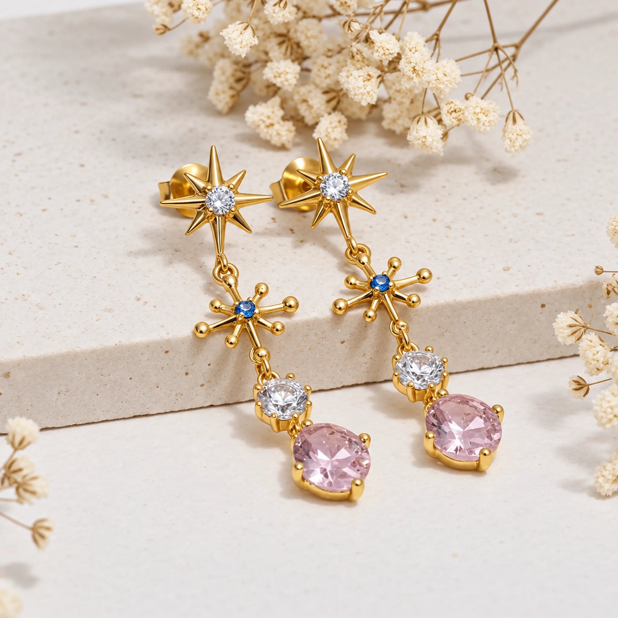 Gold multi gemstone drop earrings with pink rose quartz on a light background