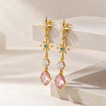 Pair of gold gemstone drop earrings on a beige surface