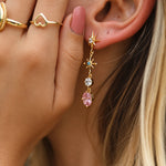 Woman wearing gold white topaz, rose quartz and sapphire drop earrings