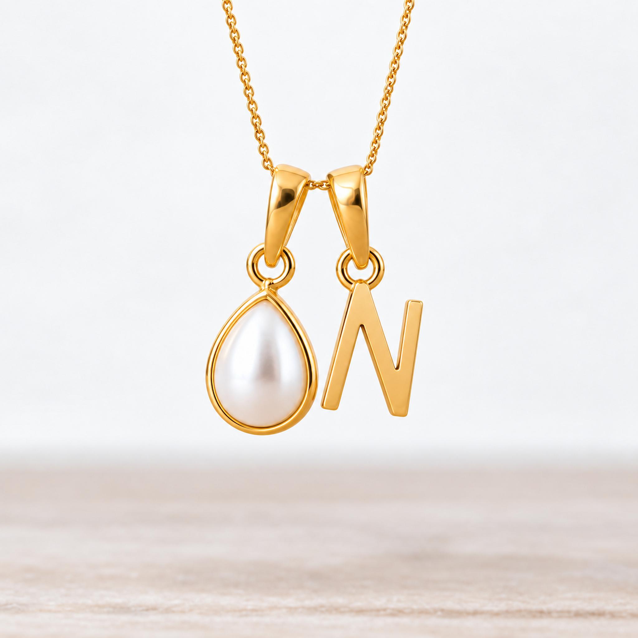 Gold June birthstone necklace with a pear-shaped natural mother of pearl pendant and letter 'N' charm.
