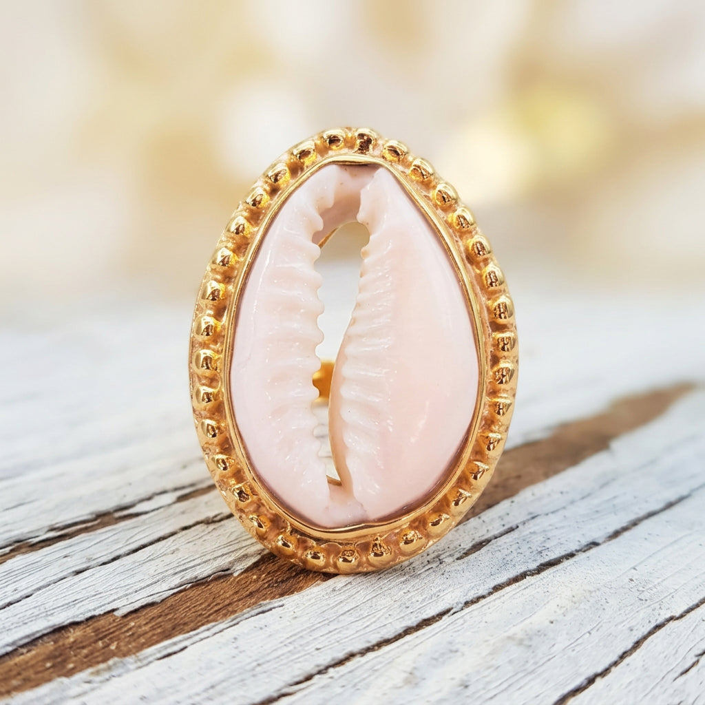 Gold cowrie sea shell ring on rustic wood