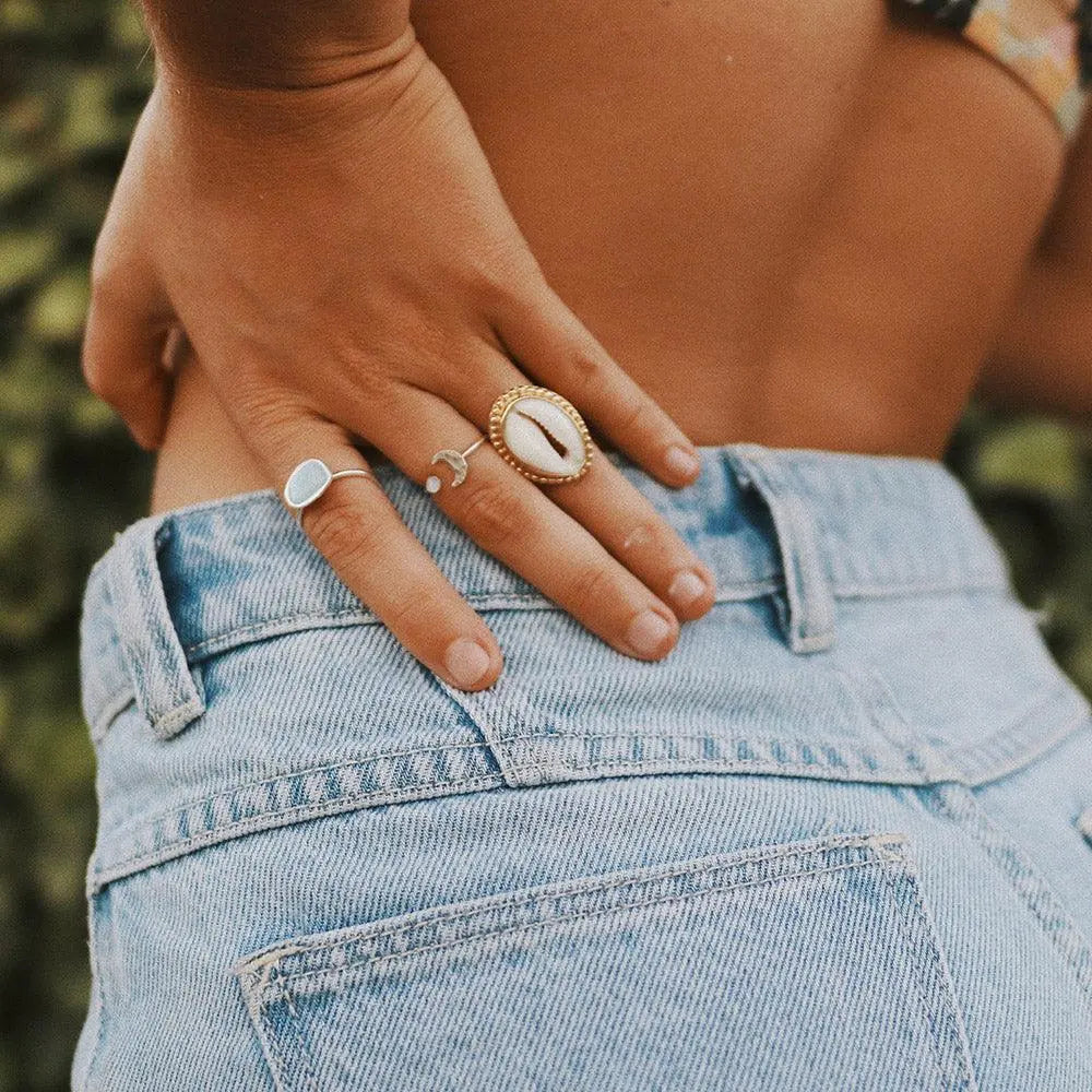 Hand wearing the gold cowrie shell ring
