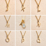 Gold necklaces with letters J to Q on a beige background showing the personalised gold letters available for the November Birthstone Blue Topaz Necklace.