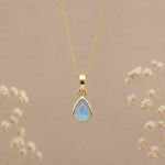 gold november birthstone topaz necklace with a dainty pear-shaped cabochon bezel set natural light blue topaz gemstone hanging