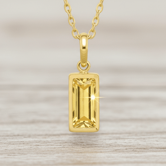 Gold pendant necklace with a rectangular gemstone on a white background