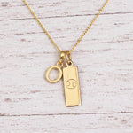 Gold Initial O Pendant and Cancer Zodiac Pendant Necklace on a fine gold chain against a light wooden background
