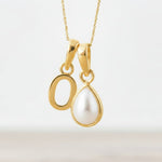 Gold necklace with a Gold Initial O and tear drop Pearl pendant on a light background