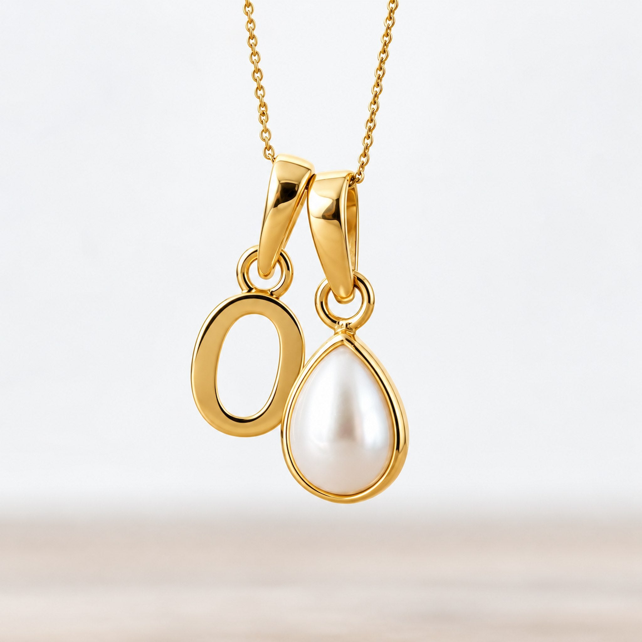 Gold June birthstone necklace with a pear-shaped natural mother of pearl pendant and letter 'O' charm.