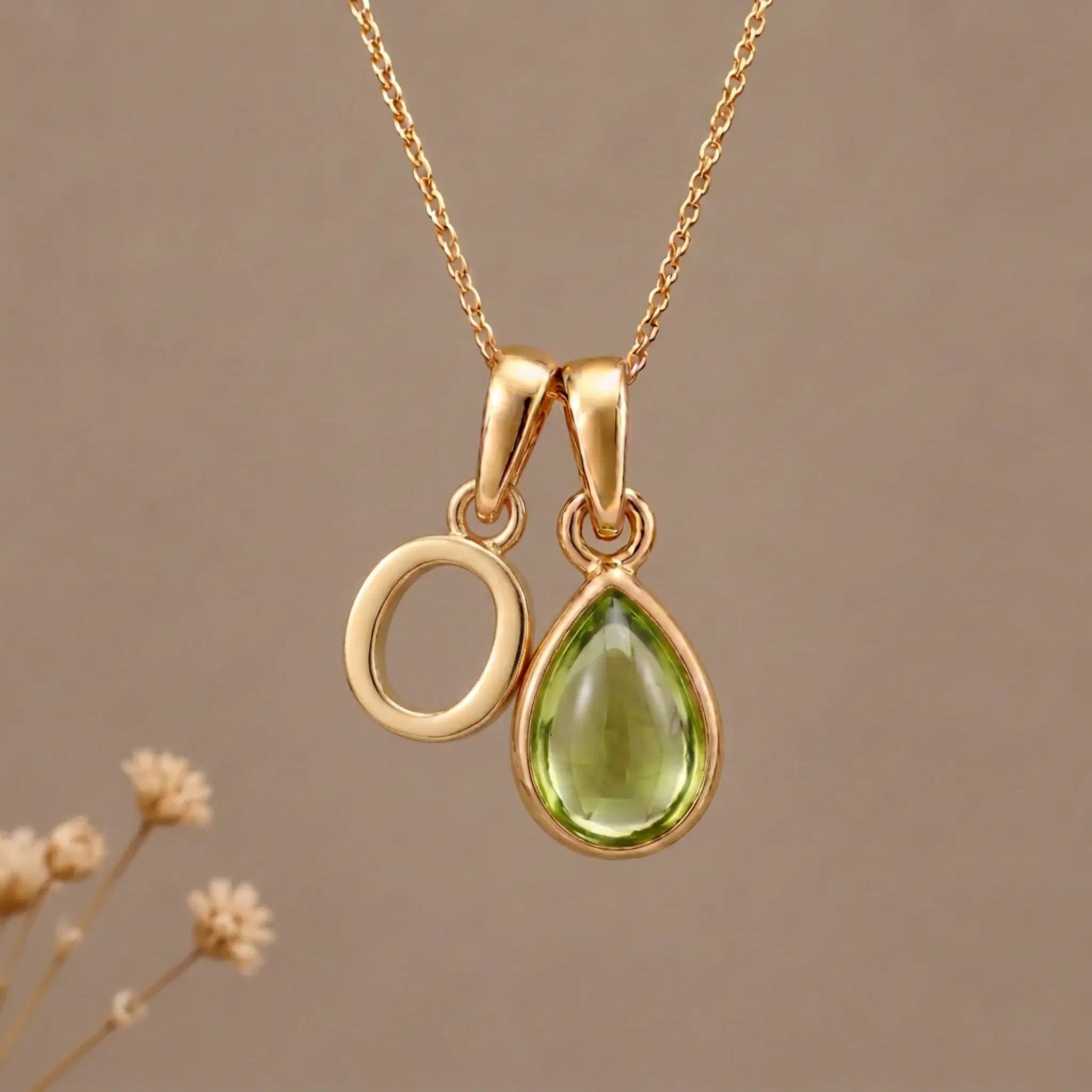 Gold Initial O Pendant and August birthstone Natural Peridot Necklace against a warm background