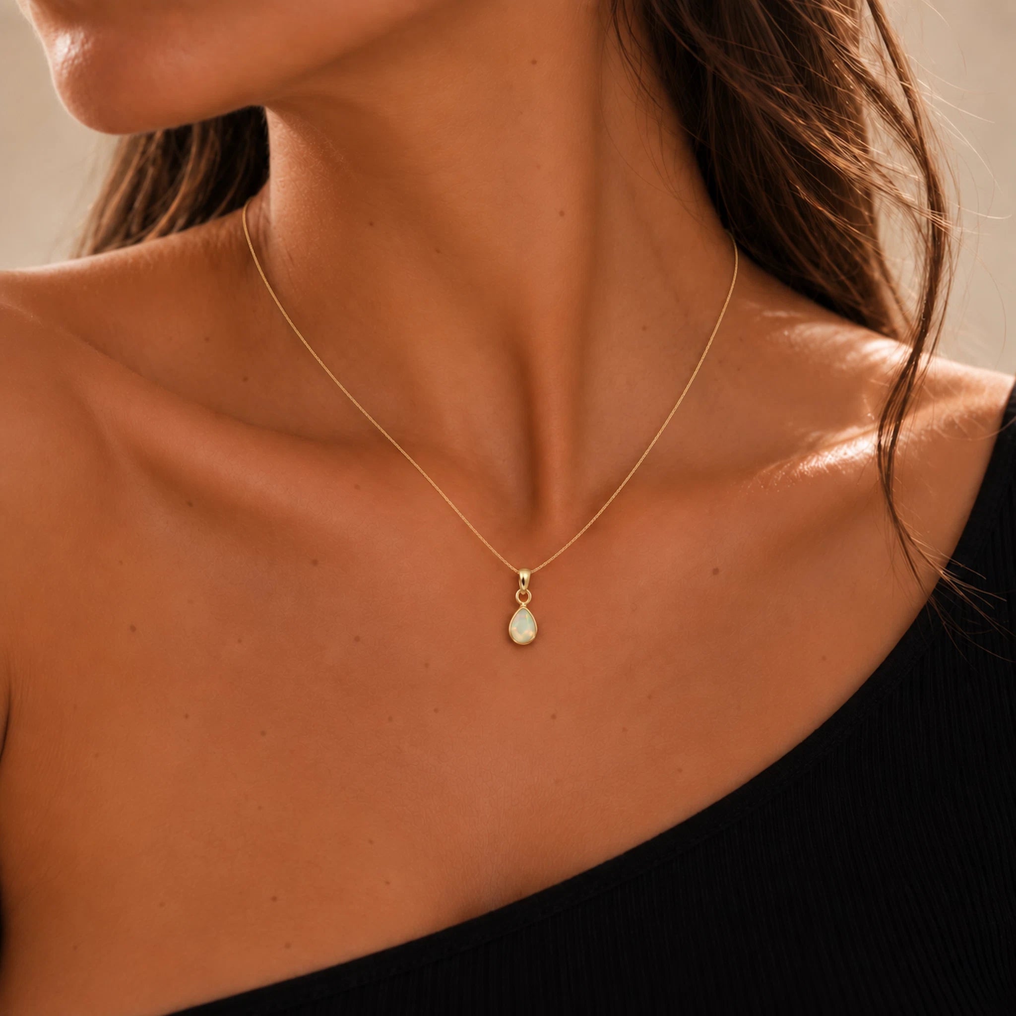 model wearing a gold october birthstone necklace with a dainty teardrop natural opal pendant