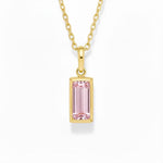 gold october birthstone necklace with pink cubic zirconia on a white background.
