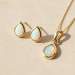 Gold October Birthstone opal stud earrings and opal necklace on a light stone surface
