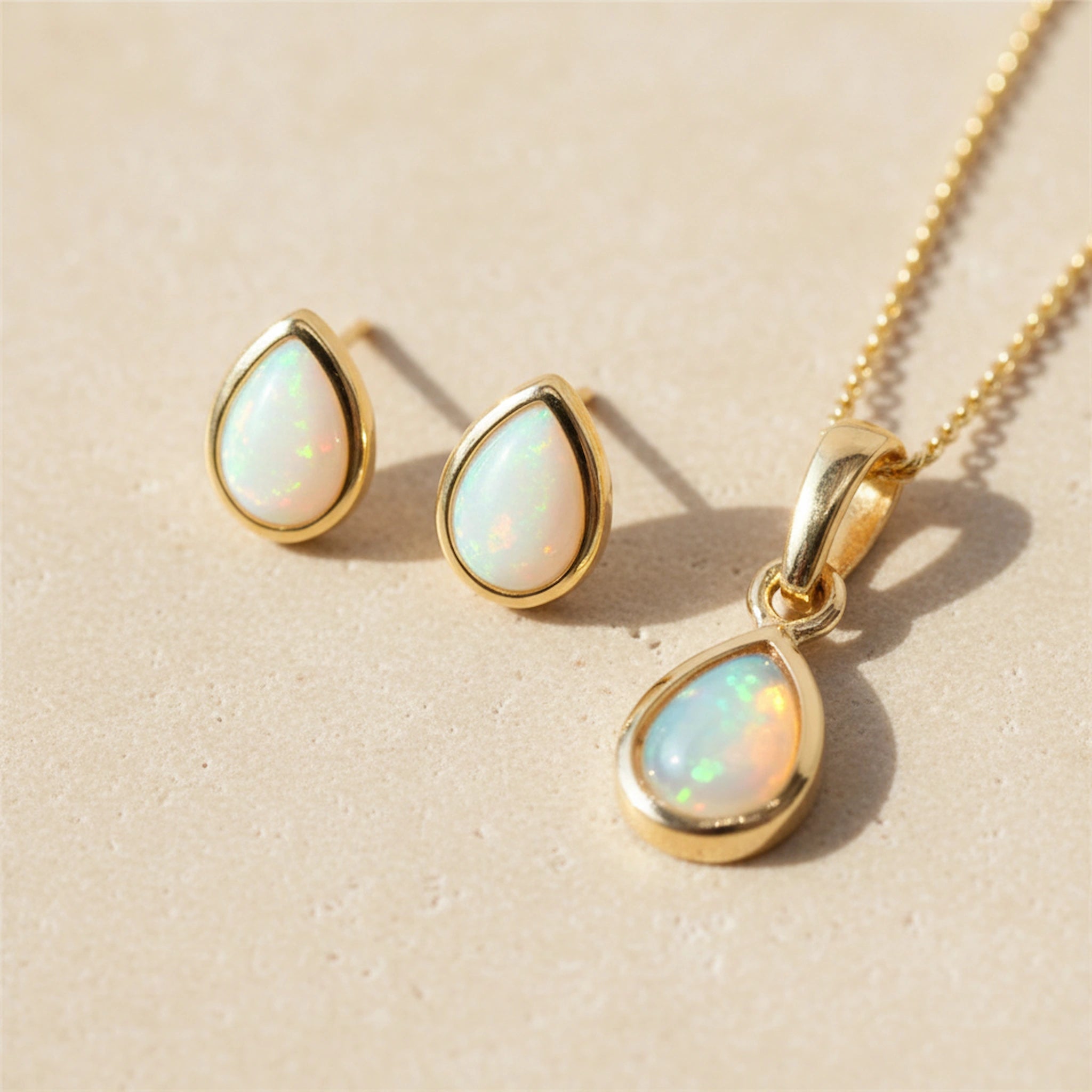 Gold jewelry set with opal stones on a beige background